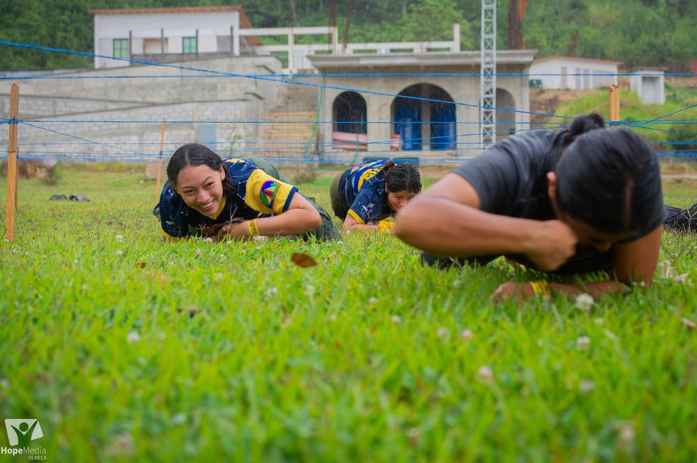 Jóvenes arrastrándose en el pasto durante un reto del camporee
